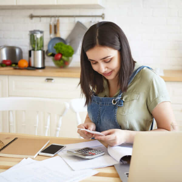 Gros plan des mains d'une personne tenant un smartphone et une carte de crédit au-dessus d'un bureau avec des documents, évaluant quand utiliser ce type de financement.